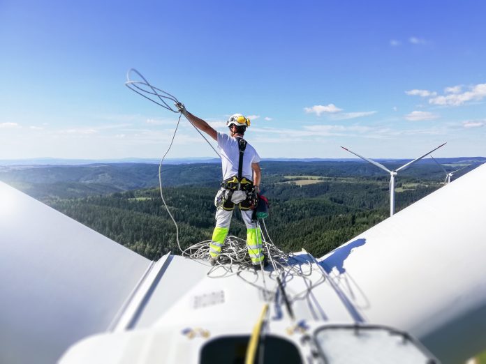 ECITB launches new version of CCNSG Safety Passport course Professional rope access technician standing on roof (hub) of wind turbine and pulling rope up, representing the CCSNG Safety Passport