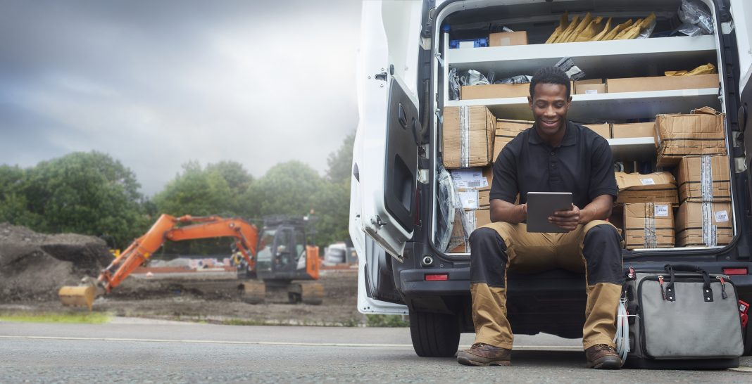 Service engineer sat on the back step of his van A Service engineer sat on the back step of his van using a digital tablet, representing safer plant training