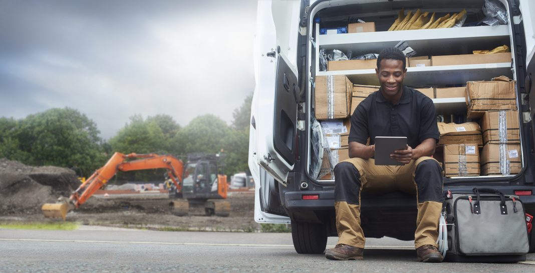 A Service engineer sat on the back step of his van using a digital tablet, representing safer plant training