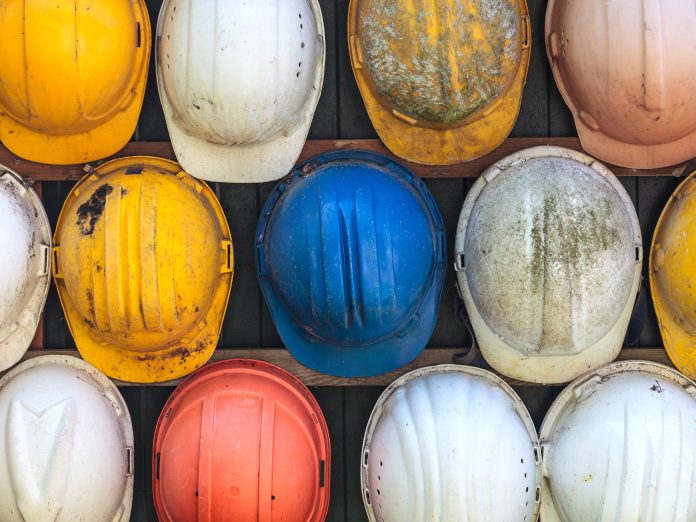 1 in 4 construction workers consider themselves neurodiverse Old and worn colorful construction helmets, representing neurodiverse construction workers