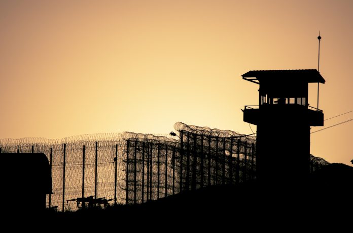 Silhouette of barbed wires and watchtower of prison in Neapolis, Crete, at sunset