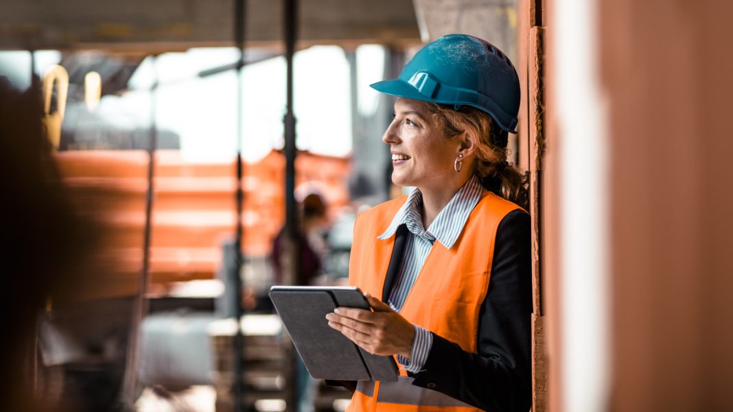 Portrait of a young female supervisor Portrait of a young female supervisor. Behind her engineer and construction worker looking some details, representing the BW Partner Program