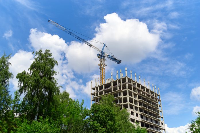 Construction site, building and trees, crane, blue sky Construction site, building and trees, crane, blue sky, representing the biodiversity net gain deadline