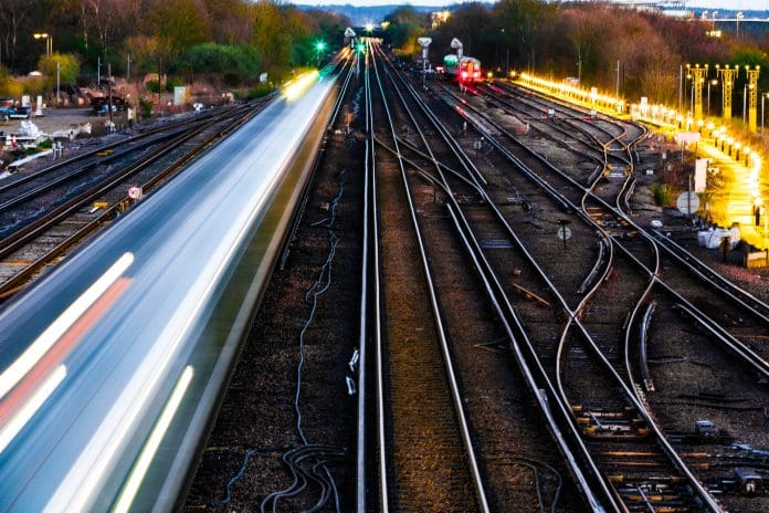 High angle view of blurred motion and light trails of a passenger train in the early evening, representing network rail frameworks