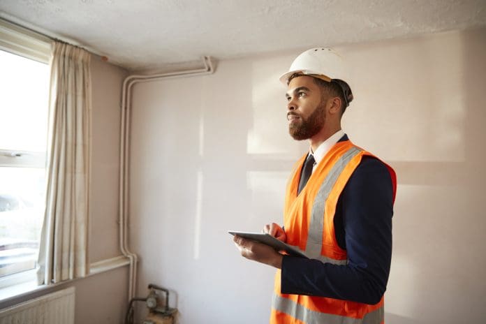 Building safety legislation: everything, all at once Surveyor In Hard Hat And High Visibility Jacket With Digital Tablet Carrying Out House Inspection