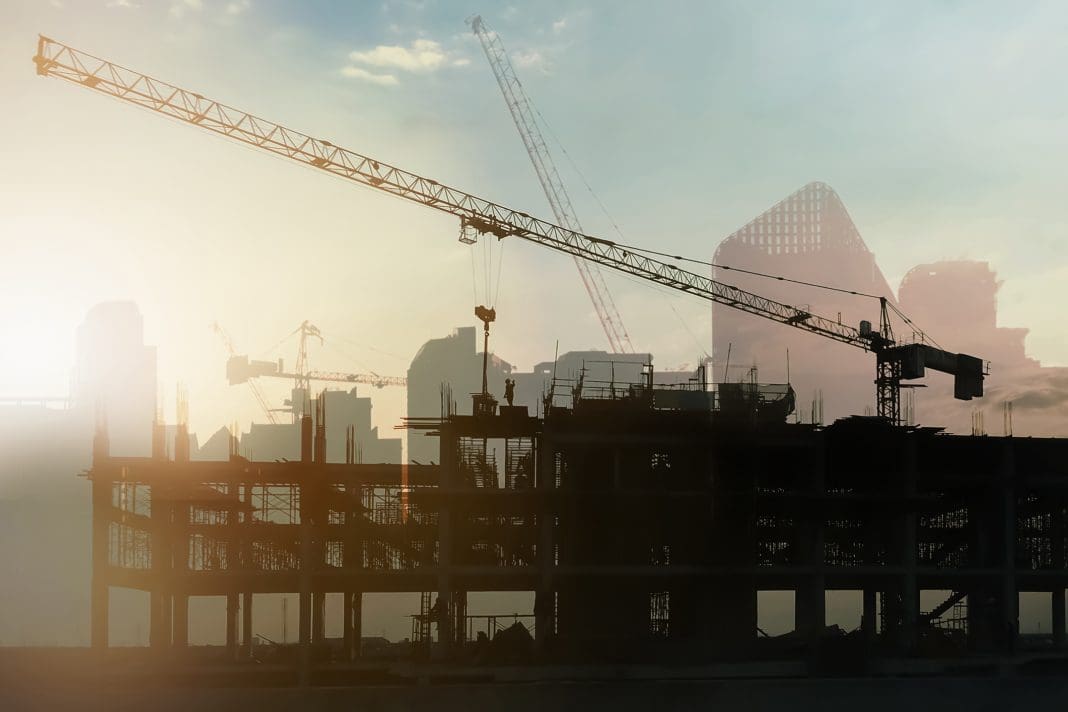 Double exposure image of silhouette building construction site with tower crane working on twilight time for construction industry and technology presentation background, representing the Whole Life Carbon Assessment Standard