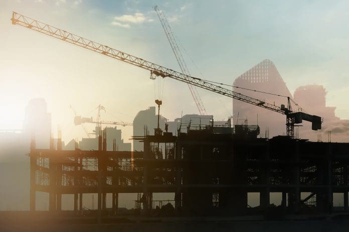 Building a consistent, sustainable future with the Whole Life Carbon Assessment Standard Double exposure image of silhouette building construction site with tower crane working on twilight time for construction industry and technology presentation background, representing the Whole Life Carbon Assessment Standard