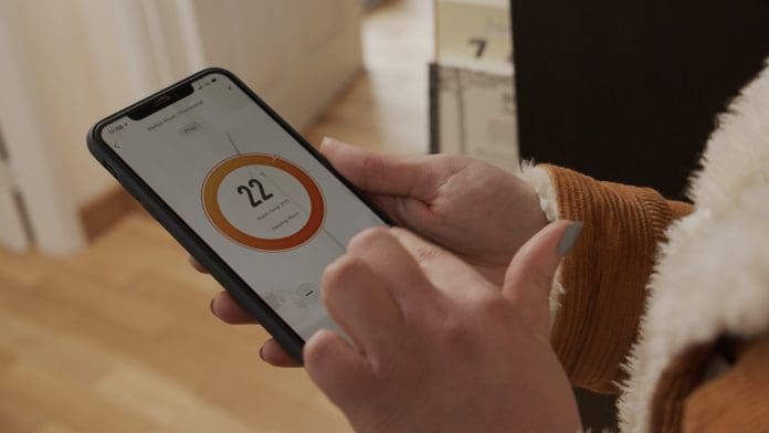 Person holding a phone with energy reading on it, representing infrared heating