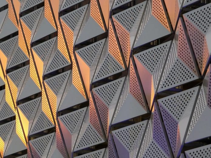 OpenSpace unveils new timelapse video feature for showcasing projects modern steel cladding with angular geometric patterns and square holes in a shiny metallic finish with colored reflection on the wall of a car park in leeds university district
