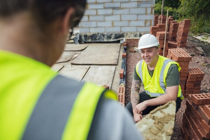 A close-up shot of a Caucasian male construction worker having a conversation with a colleague onsite