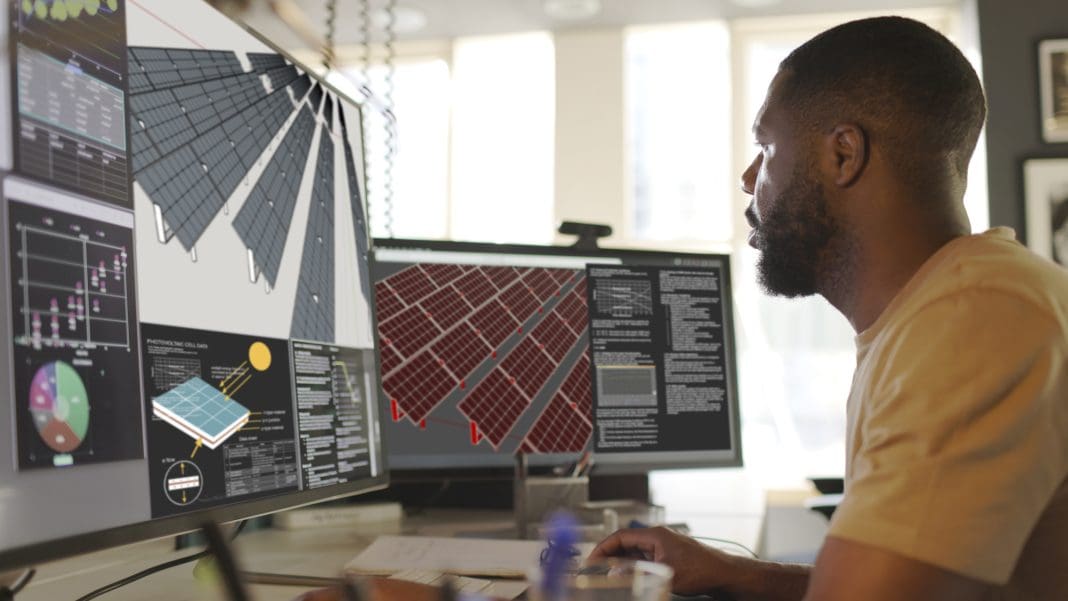 Close up stock image of an African American man working at a computer screen. He’s working on CAD software looking at the design of a solar panel array in CAD with data, representing construction data