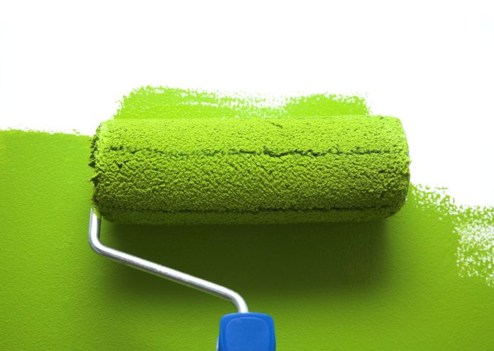 painting with green paint roller, representing greenwashing