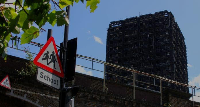 Why the Building Safety Act will affect more than just HRBs Grenfell Tower in the background, Children crossing sign in the foreground, reminder of the children affected and who lived in the neighborhood.