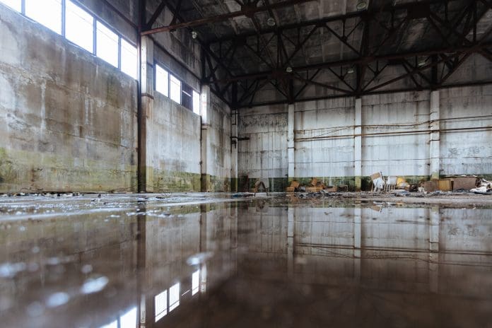 Commercial flood risk: parametric flood insurance explained with Tysers Inside of flooded dirty abandoned ruined industrial building with water reflection, representing need for parametric flood insurance