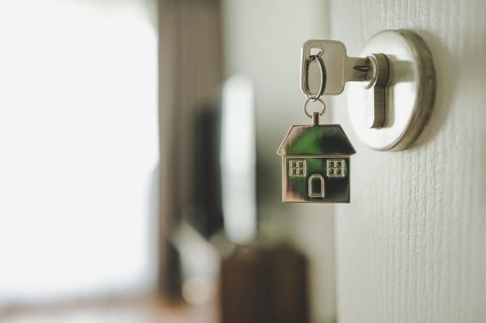Open the door and door handle with a key and a keychain shaped house. Property investment and house mortgage financial real estate concept Open the door and door handle with a key and a keychain shaped house. Property investment and house mortgage financial real estate concept