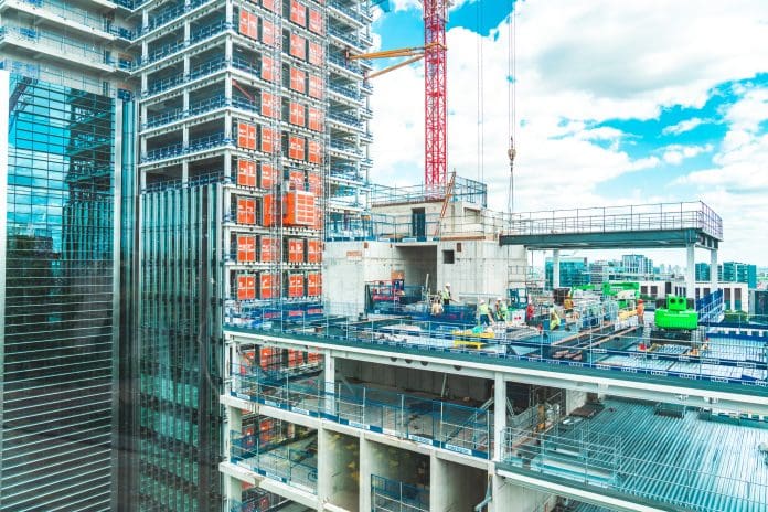 2024 construction outlook: Anticipating changes and challenges for passive fire protection View at construction site with unfinished residential buildings against blue sky, London