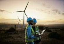 UK engineering and construction sector lags behind in decarbonisation progress Laptop, farm and engineer team together at night for renewable energy, power and wind turbine. Electrician or technician man and woman in nature for electricity, eco and green environment maintenance