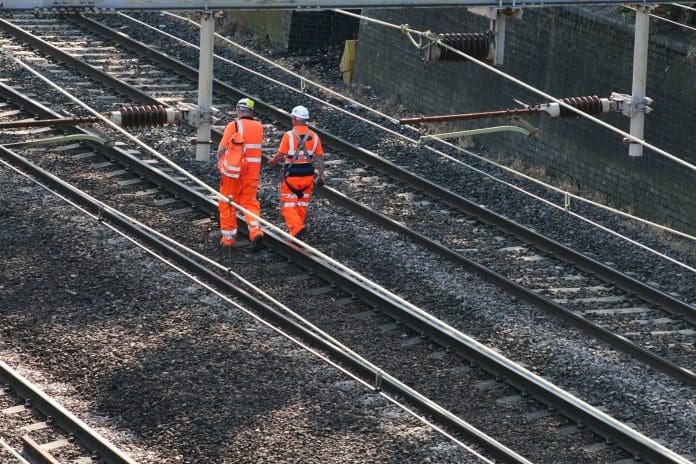 "London, United Kingdom - July 02, 2009:Picture of two male railway workers, dressed in hardhats and refelctive safety uniform walking on the tracks. The picture was taken at 9:14am in Forest Gate near Stratford home of the London 2012 Olympics." representing UK transport infrastructure
