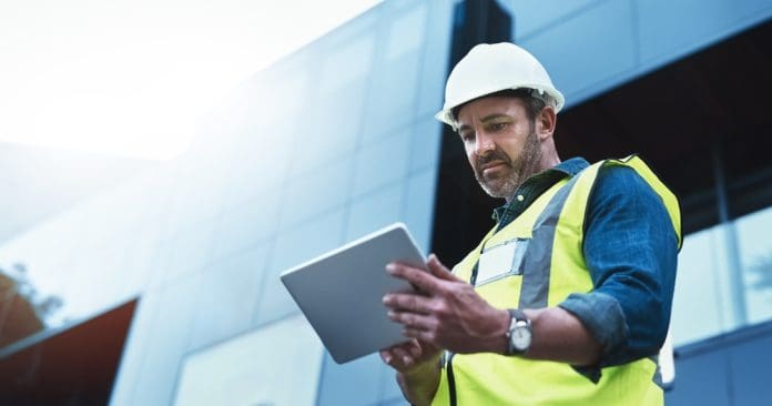 man in hardhat using tablet, representing payment management