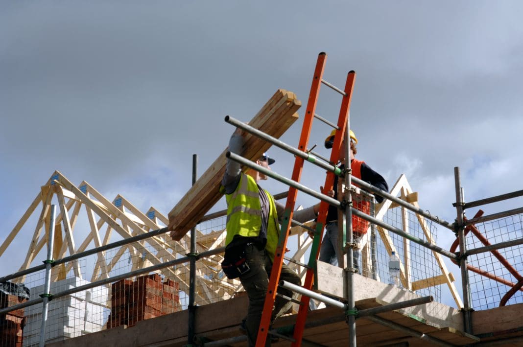A pair of roofers working on a construction site in Manchester, England, representing december construction output