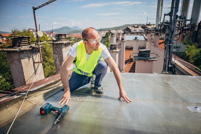 One mature man, roofer, installing a new flat roof on residential home.