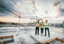 Building Control transformation: Broste Rivers innovative journey Employees working on construction site, wearing protective equipment and discussing next construction phase - full length models visible on the image