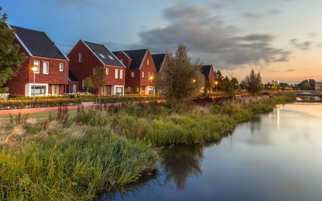 Long exposure night shot of Street with modern ecological middle class family houses with eco friendly river bank in Veenendaal city, Netherlands.