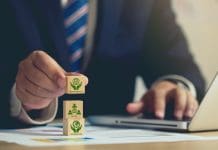 Green building certifications: Are they lowering carbon emissions or boosting building values? ESG concept of environmental, Businessman hand holding wooden cube block with ESG icon with copy space, Businessman Planing an ESG Project on laptop. Green Energy, Renewable and Sustainable Resources.