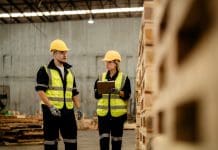 Tackling delays and price inflation in materials procurement with digital workers man and woman engineering walking and inspecting timbers wood in warehouse. Concept of smart industry worker operating. Wood factories produce wood palate. Representing materials procurement