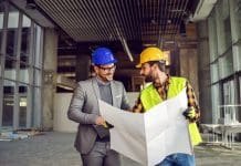 BW Build Warranty®: An attractive alternative to traditional warranties Smiling supervisor talking to construction worker about construction works. Worker holding blueprints and explaining to supervisor, representing structural warranties