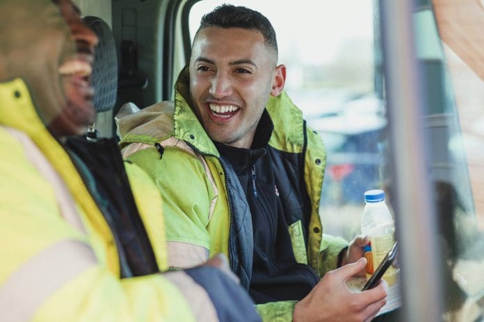 Young man and his father are talking and laughing in their work truck together, representing hiring those with criminal records