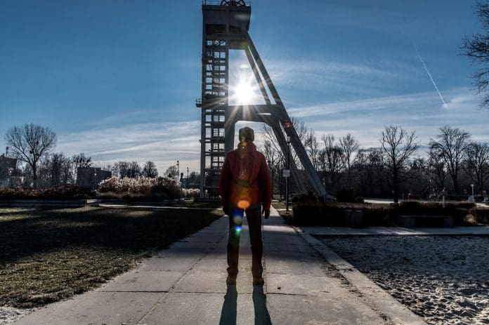 Newforma to deep dive into AECO collaboration success strategies in upcoming PBC webinar A man in a red winter anorak watching the sunrays through the structure of a mine shaft in the Silesia landscape representing aeco collaboration