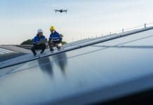 AI in construction: Transforming speed and communication Specialist technician professional engineercontrol drone checking top view of installing solar roof panel on the factory rooftop under sunlight. Engineers holding tablet check solar roof, representing AI in construction