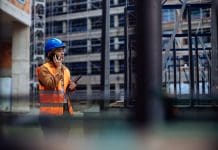 The impact of fluctuating interest rates on funding for property developers Young female worker having a phone call at a construction site