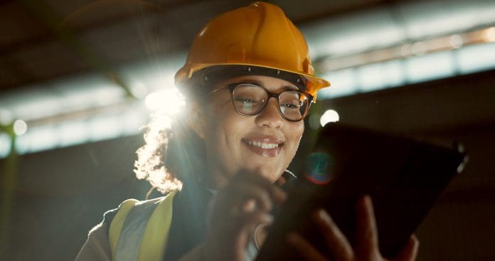 Smart construction and the rise of digital twins in the building industry Happy woman, engineer and tablet in warehouse for inspection, inventory or storage. Face of female person, architect or contractor smile on technology for quality control, communication or management