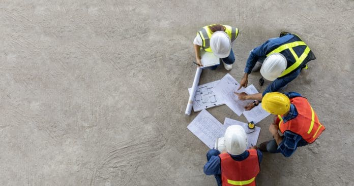Why data holds the key to unlocking development opportunities Top view of engineer, architect, contractor and foreman meeting at the construction building site with floor plan for real estate development project industry and housing timeline usage