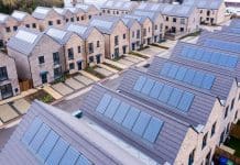 Simplifying energy efficiency policy for sustainable construction Aerial view of rows of energy efficient new build modular terraced houses in the UK with characterless design and in built rooftop solar panels for first time buyers