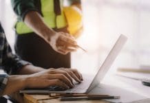 55 day payment deadline for £5m public projects takes effect business man hand working and laptop with on on architectural project at construction site at desk in office.