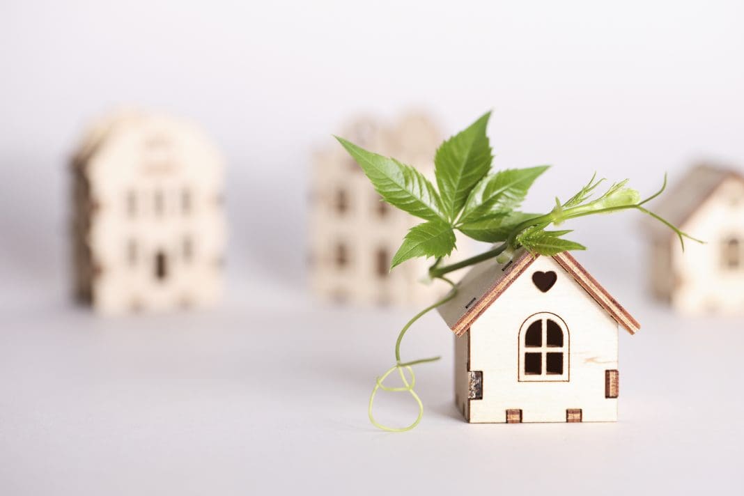 retrofit movement, future proofing homes, net zero carbon, adapting buildings concept. toy houses with green leaf on roof on white background. retrofit movement, future proofing homes, net zero carbon, adapting buildings concept. toy houses with green leaf on roof on white background.