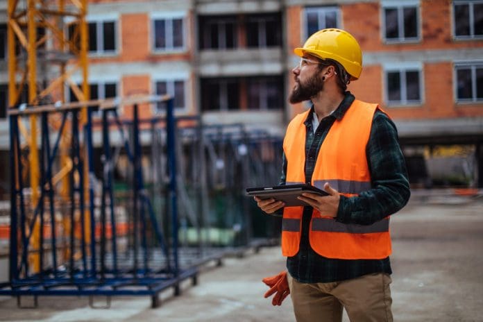 Young construction worker using his digital tablet while at a building site