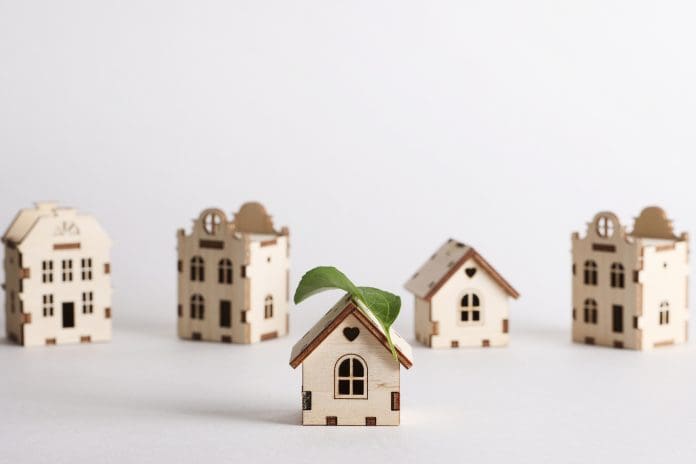 retrofit movement, future proofing homes, net zero carbon, adapting buildings concept. toy houses with green leaf on roof on white background. retrofit movement, future proofing homes, net zero carbon, adapting buildings concept. toy houses with green leaf on roof on white background.