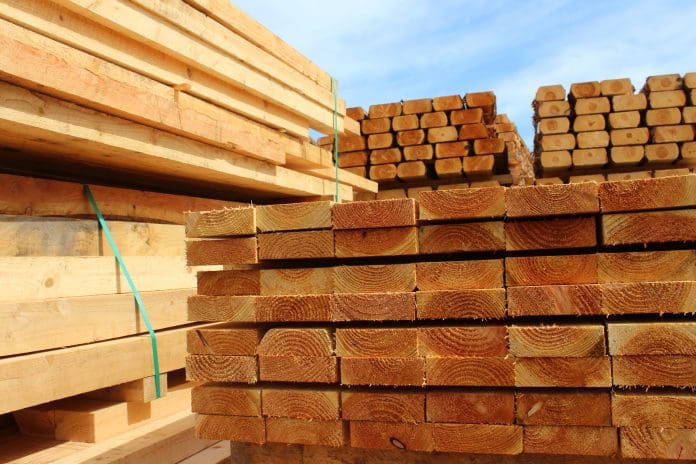 Photo showing some huge piles of wooden planks and fence posts, freshly sawn up in a sawmill and piled in the timber yard, ready to be sold to the general public.