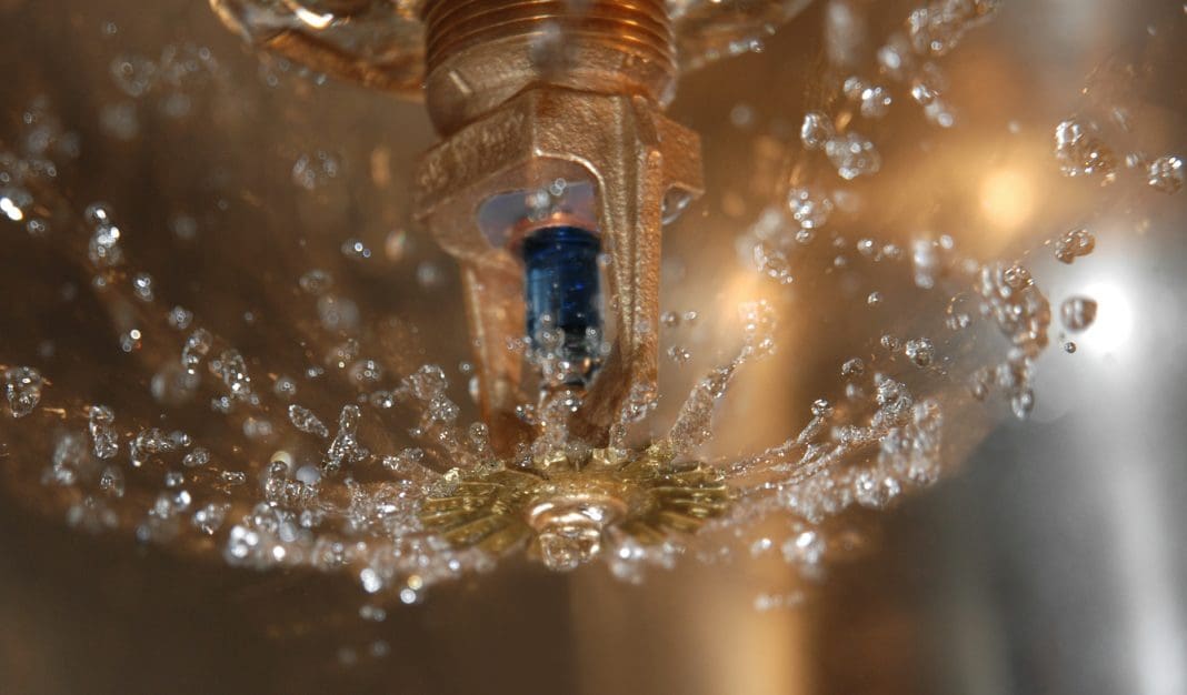 Water spraying from a fire sprinkler in close-up.