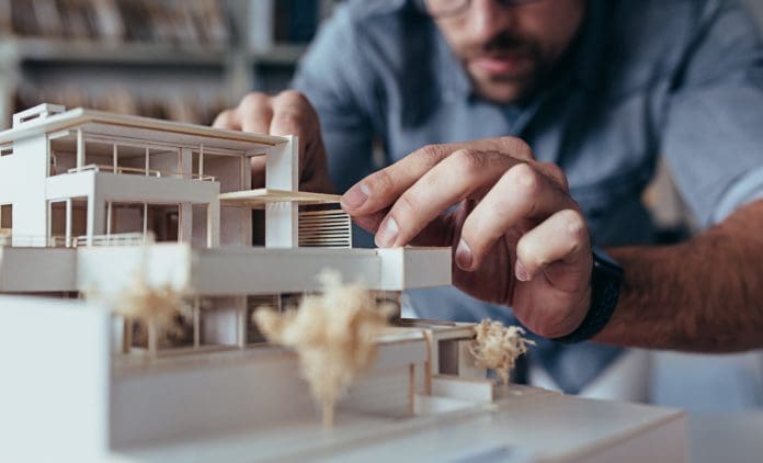 Male architect hands making model house Close up of male architect hands making model house. Man architect working in the office.