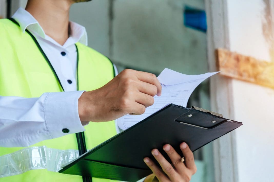engineer or home inspector in green reflective jacket checking review document and inspecting with clipboard at construction site building interior, construction, contractor and engineering concept adapting insurance strategies