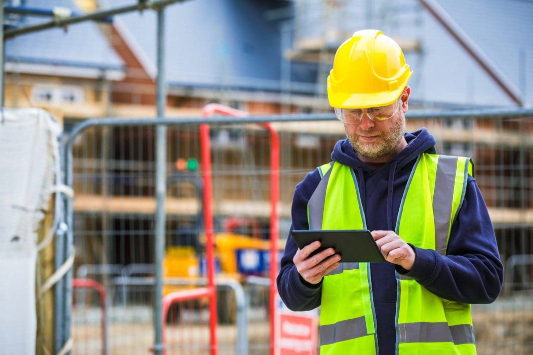 Construction worker using digital tablet on building site