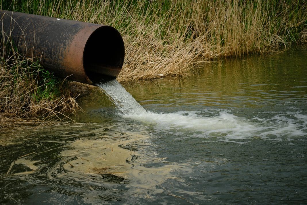 Draining sewage from pipe into river, pollution rivers and ecology. sewage dumping