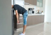 Majority of engineers unfamiliar with overheating home regulations Man desperate to cool down with head in refrigerator, a symptom of overheating homes
