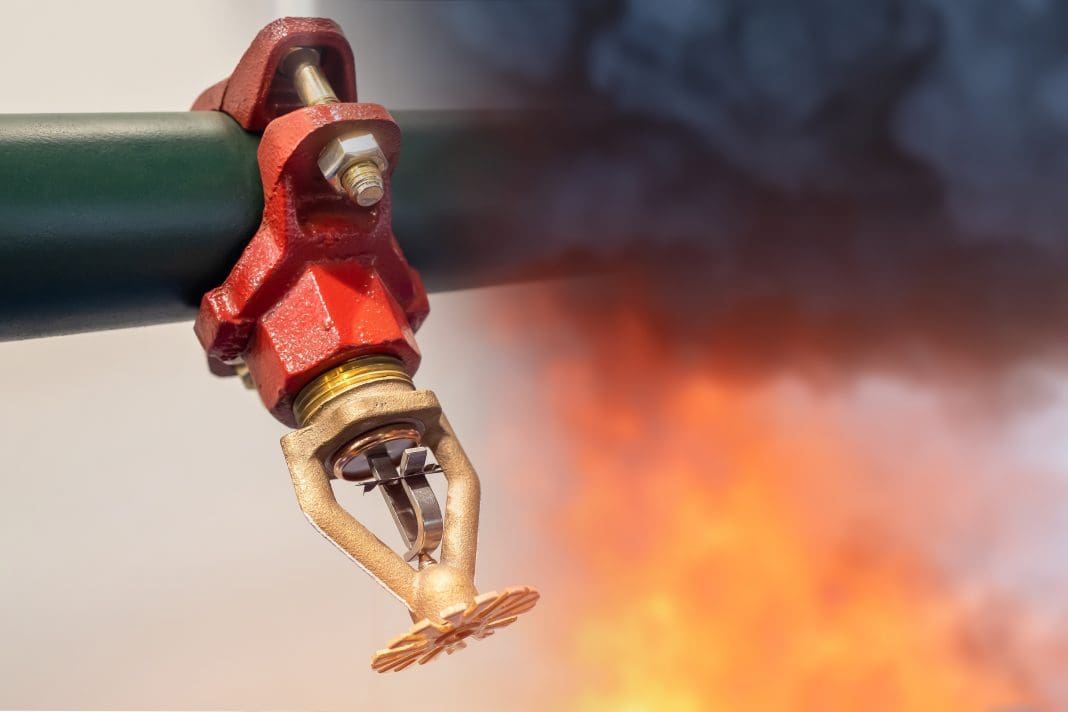 Sprinkler,For,Fire,Extinguishing,System.,Sprinkler,Next,To,Flame,And Fire sprinklers and fire, highlighting the importance of sprinkler systems