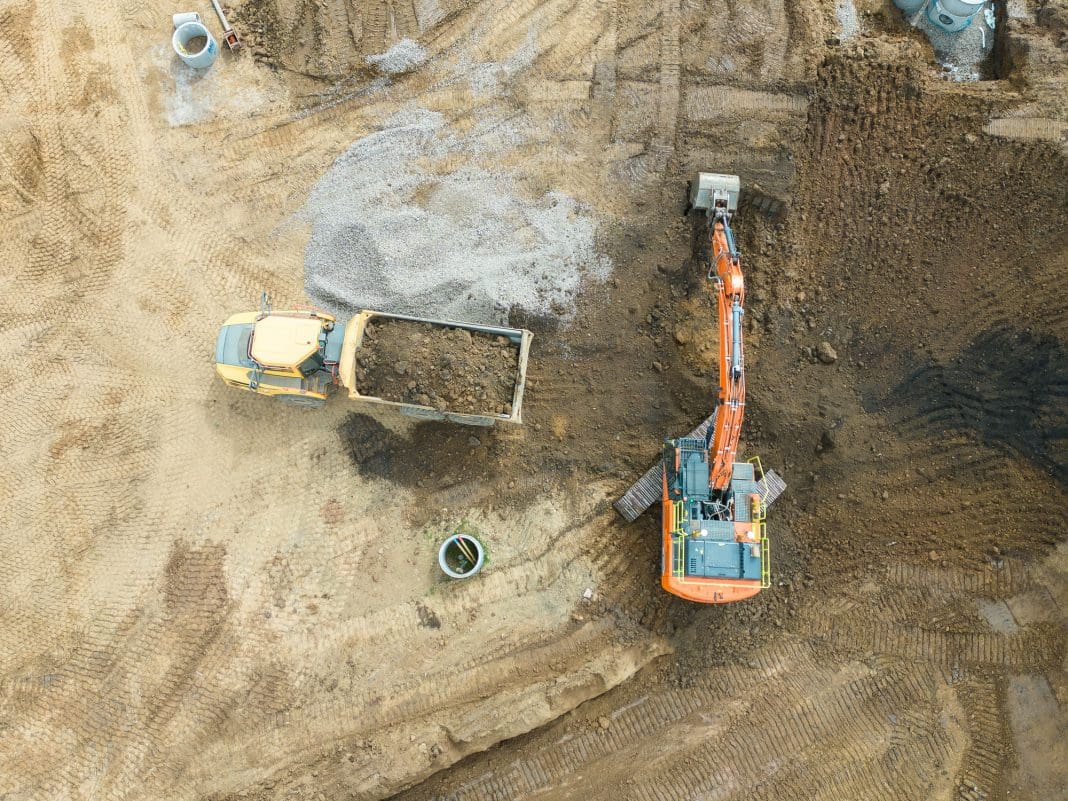 Aerial view of a bulldozer scraping up soil to load onto a dumper truck Glenigan September review shows construction starts are down
